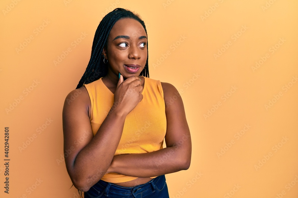 Obraz premium Young african american woman wearing casual clothes with hand on chin thinking about question, pensive expression. smiling with thoughtful face. doubt concept.