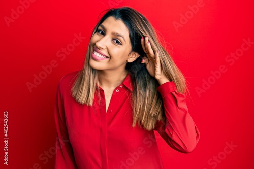 Beautiful brunette woman wearing casual clothes smiling with hand over ear listening and hearing to rumor or gossip. deafness concept.