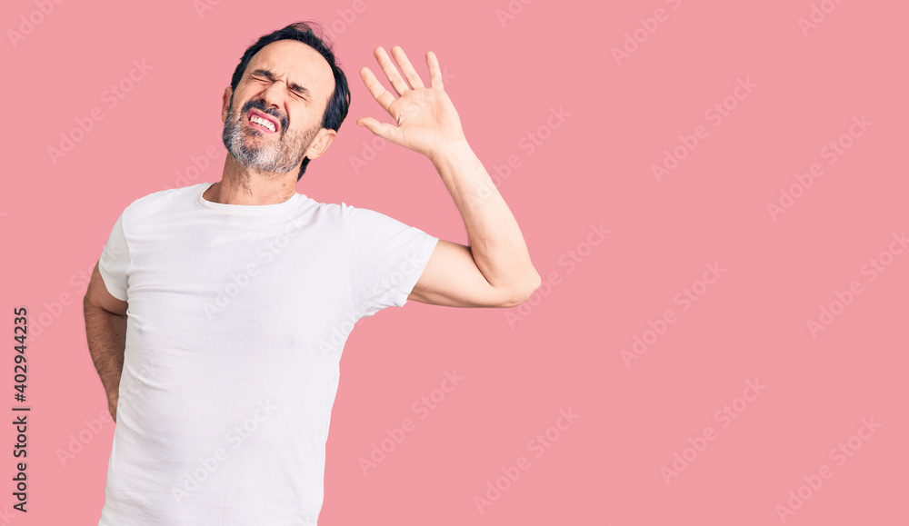 Middle age handsome man wearing casual t-shirt stretching back, tired and relaxed, sleepy and yawning for early morning Middle age handsome man wearing casual t-shirt stretching back, tired and relaxed, sleepy and yawning for early morning