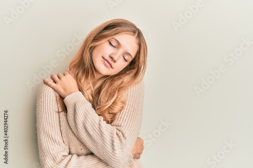 Beautiful young caucasian girl wearing casual clothes hugging oneself happy and positive, smiling confident. self love and self care