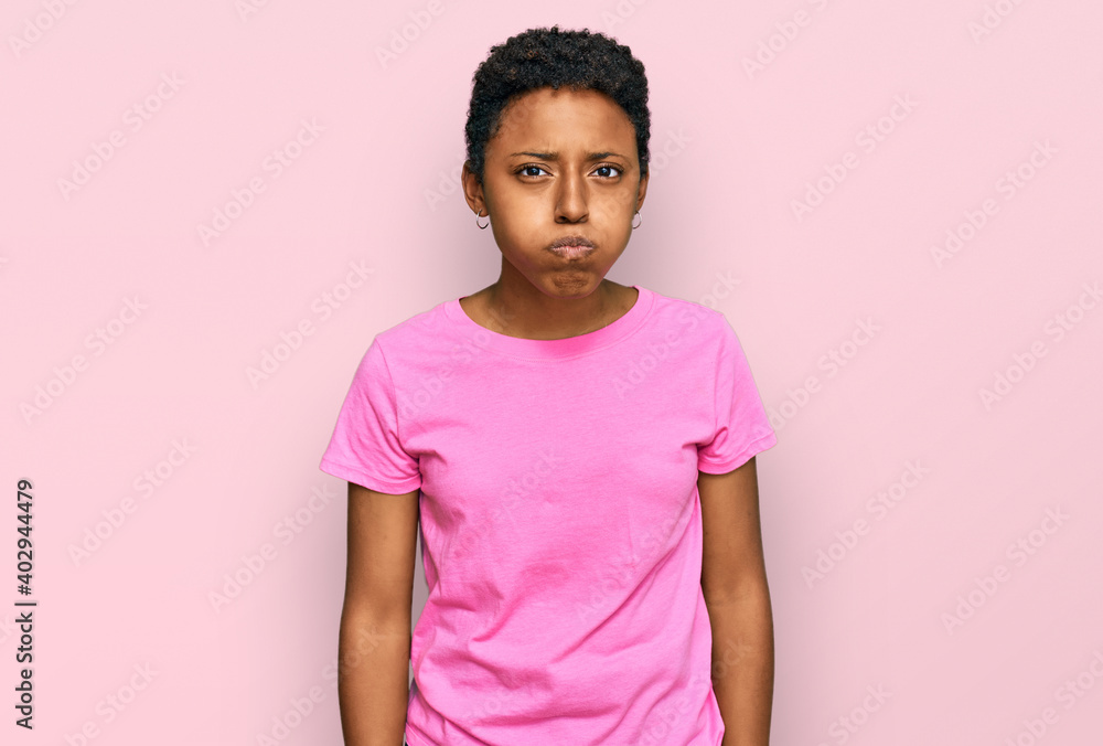 Young african american woman wearing casual clothes puffing cheeks with funny face. mouth inflated with air, crazy expression. Young african american woman wearing casual clothes puffing cheeks with funny face. mouth inflated with air, crazy expression.