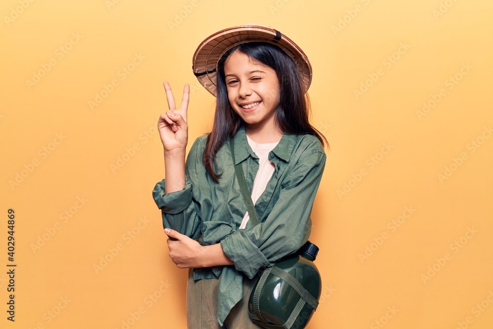 Beautiful child girl wearing explorer hat smiling with happy face winking at the camera doing victory sign. number two. Beautiful child girl wearing explorer hat smiling with happy face winking at the camera doing victory sign. number two.
