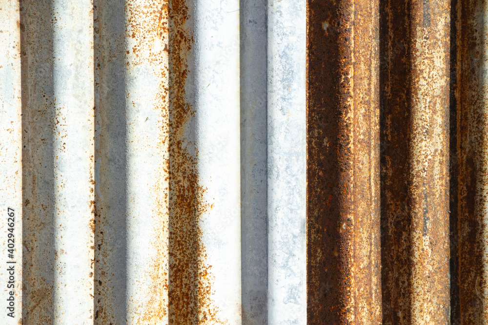 Rusted corrugated sheet metal siding background showing its age and weathering. Rusted corrugated sheet metal siding background showing its age and weathering.