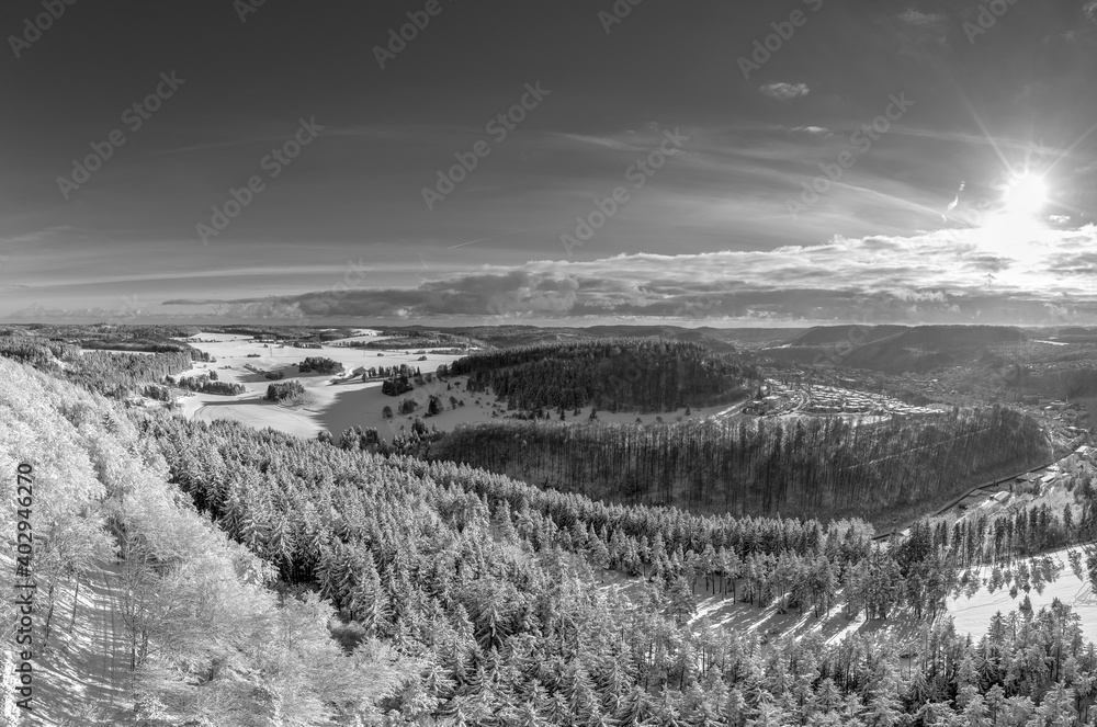 Snowy monochrome mountain winter landscape with sunny sky wide panorama.