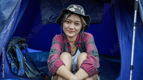 Asian woman camping at reservoir and sit down in tent