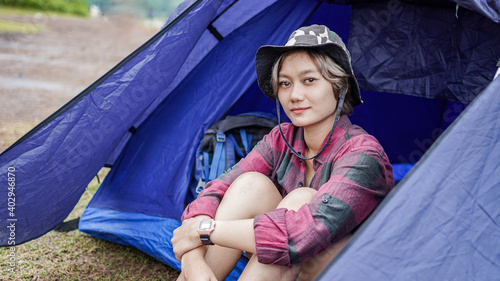 Asian woman camping at reservoir and sit down in tent