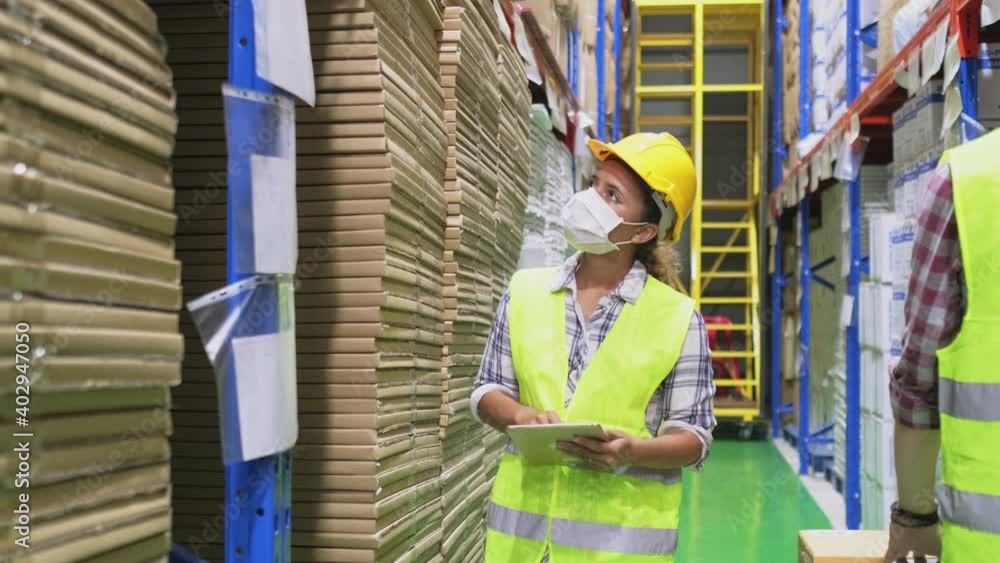 Female worker wearing face mask, using tablet for work in warehouse. Female worker wearing face mask, using tablet for work in warehouse.