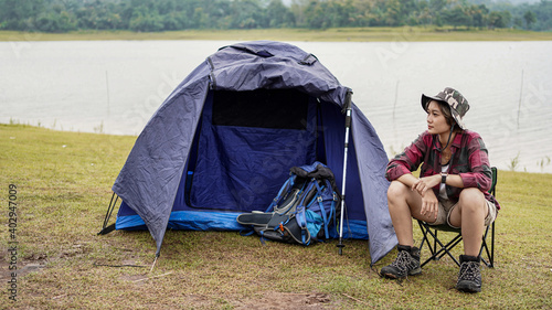Asian woman camping at reservoir and sit down in chair