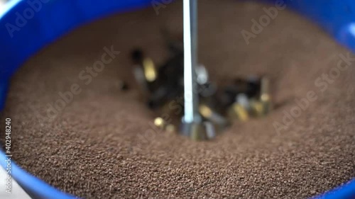 Brass bullet casings sinking into Walnut medium of Ammo Tumbler photo