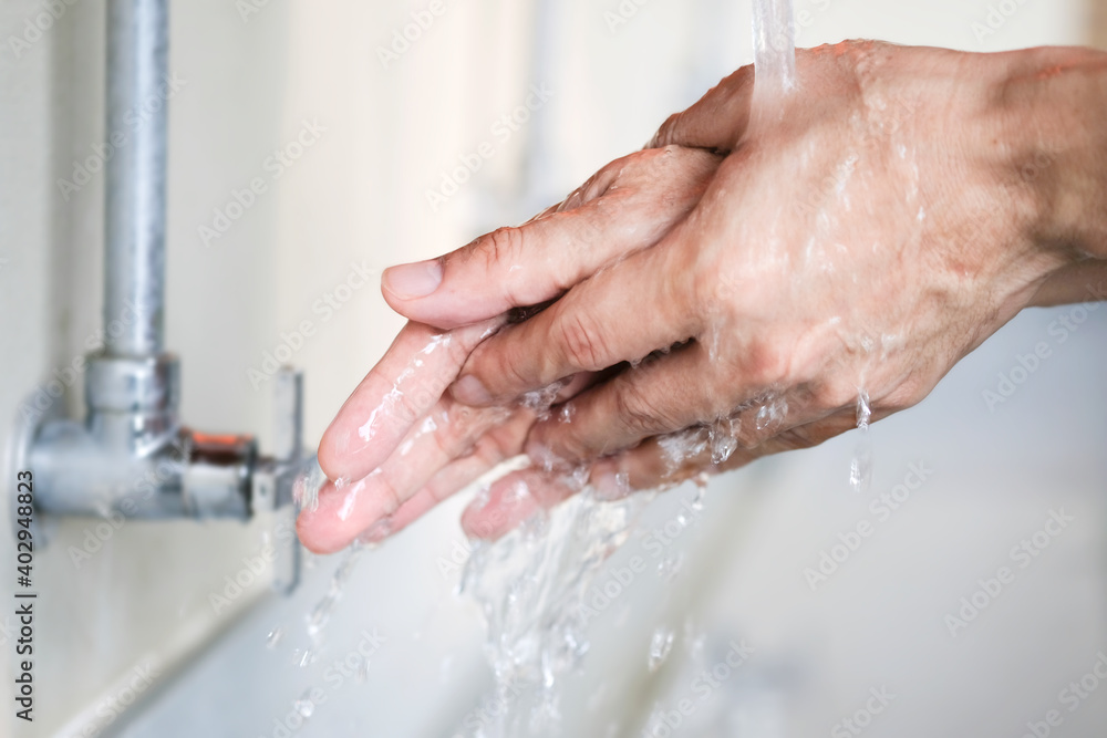 Fototapeta premium Hands of woman wash their hands in a sink with foam to wash the skin and water flows through the hands. Concept of health, cleaning and preventing germs and coronavirus from contacting hands