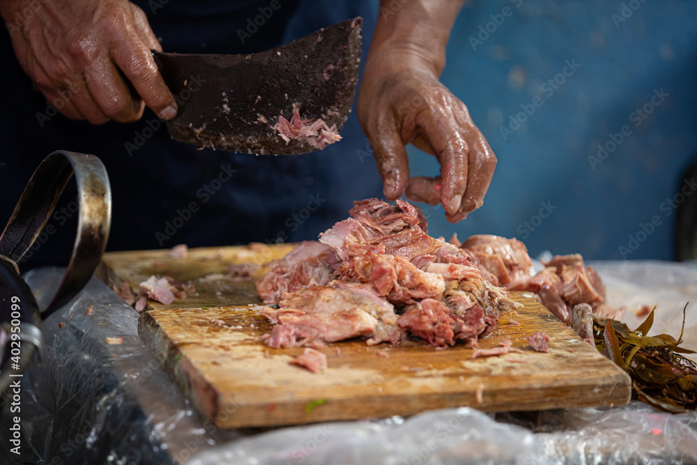 mexican man cutting pork meat