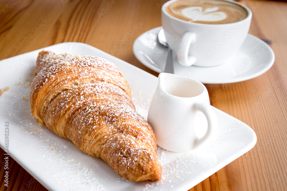 Croissant with coffee latte on wooden floor