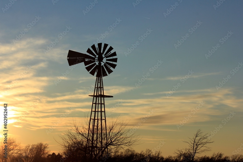 windmill at sunset with clouds and a colorful sky north of Hutchinson Kansas USA out in the country. windmill at sunset with clouds and a colorful sky north of Hutchinson Kansas USA out in the country.