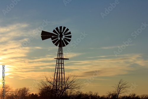 windmill at sunset with clouds and a colorful sky north of Hutchinson Kansas USA out in the country.