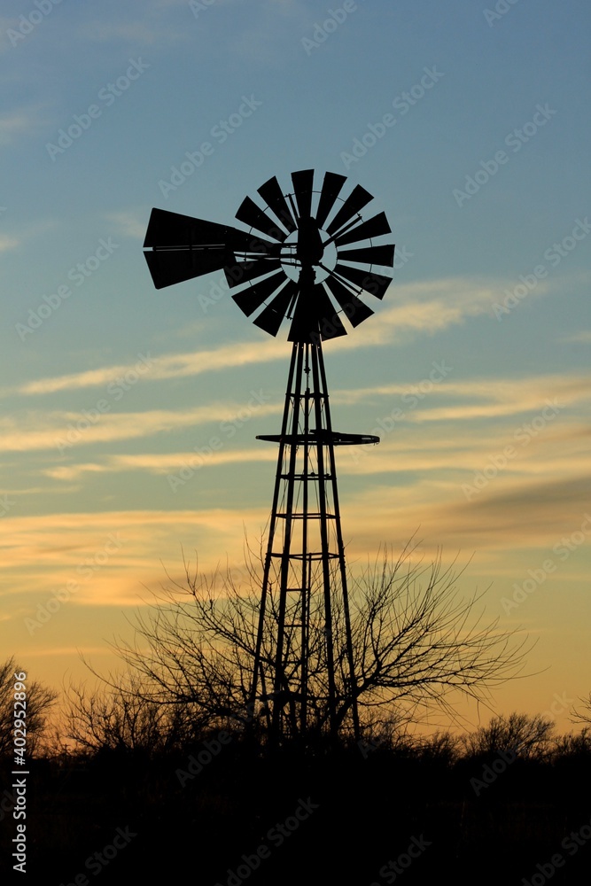 windmill at sunset with clouds and a colorful sky north of Hutchinson Kansas USA out in the country. windmill at sunset with clouds and a colorful sky north of Hutchinson Kansas USA out in the country.