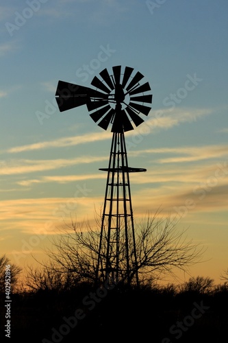 windmill at sunset with clouds and a colorful sky north of Hutchinson Kansas USA out in the country.
