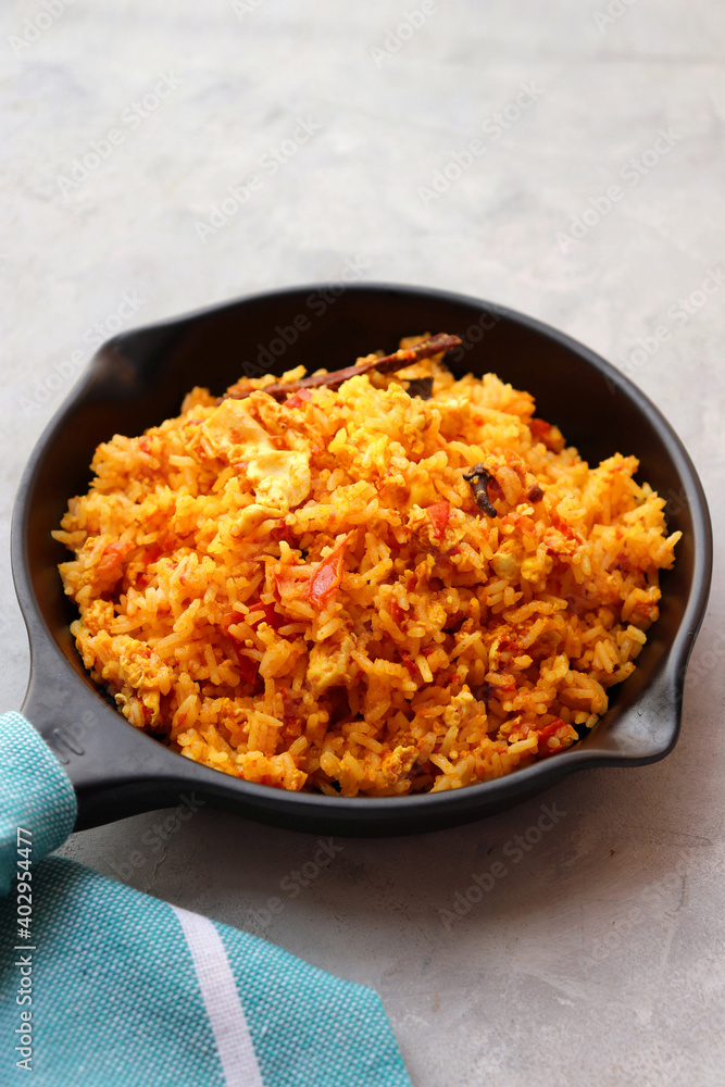 Tomato rice with eggs. Stir fried rice in spicy tomato sauce mixed with egg and spices. Served in an iron pan. Tomato rice with eggs. Stir fried rice in spicy tomato sauce mixed with egg and spices. Served in an iron pan.