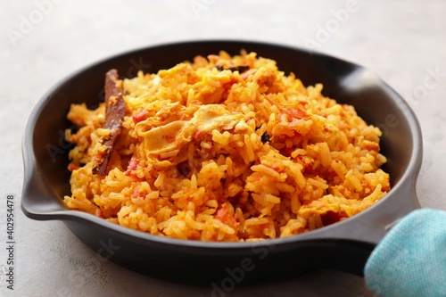 Tomato rice with eggs. Stir fried rice in spicy tomato sauce mixed with egg and spices. Served in an iron pan.