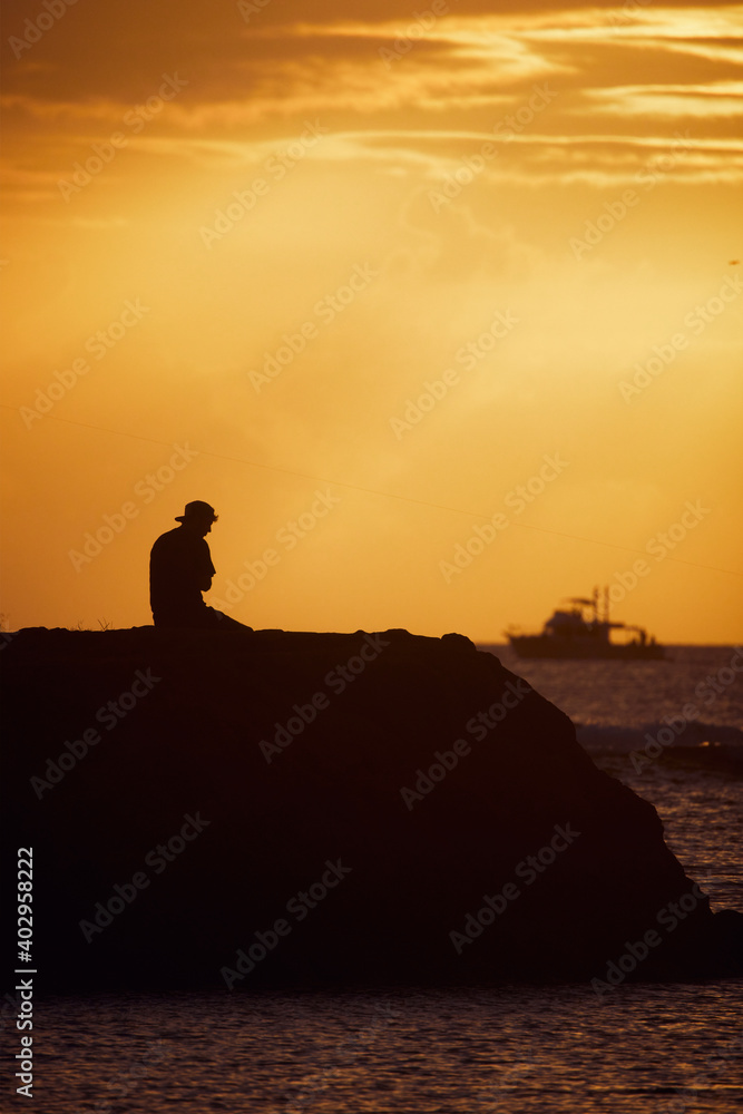 Silhouette of a man seating at sunset background. 