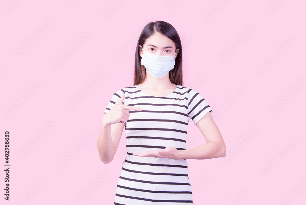 Studio image of a woman wearing a mask looking at the camera separately on a pink background. Flu epidemic, dust allergy, COVID-19 prevention, health and hygiene concept. Studio image of a woman wearing a mask looking at the camera separately on a pink background. Flu epidemic, dust allergy, COVID-19 prevention, health and hygiene concept.