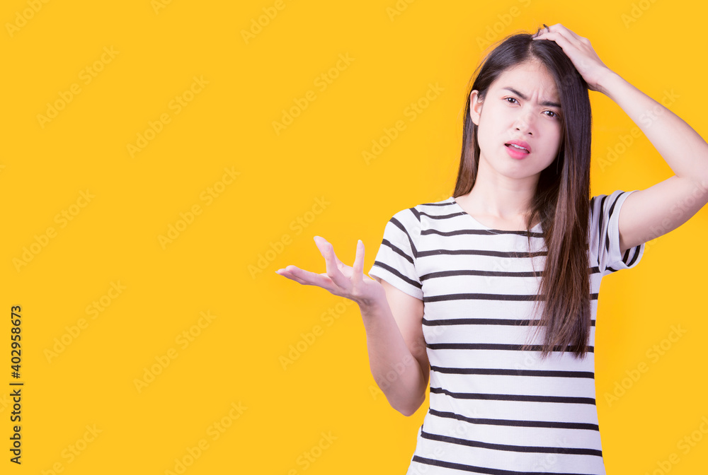Smiling asian woman pointing up and looking at the camera over yellow background Smiling asian woman pointing up and looking at the camera over yellow background