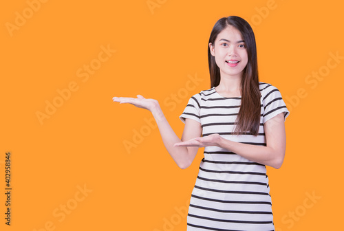Smiling asian woman pointing up and looking at the camera over yellow background