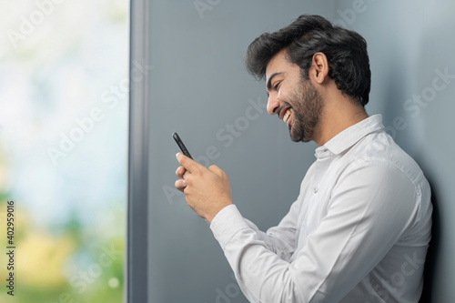A YOUNG OFFICE EXECUTIVE LAUGHING WHILE USING MOBILE PHONE	 photo