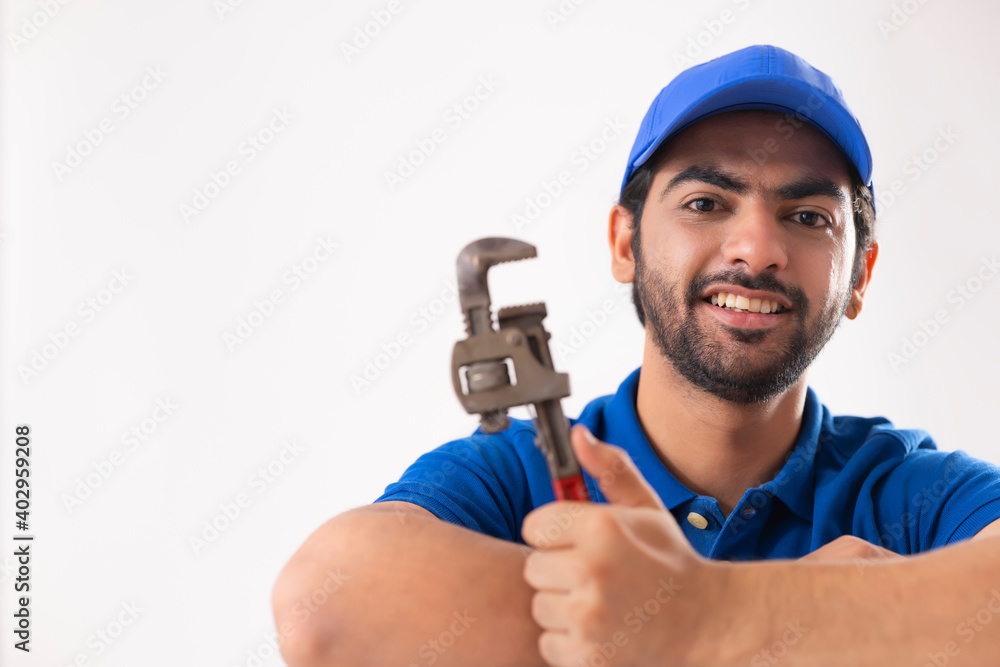 PORTRAIT OF A PLUMBER HAPPILY POSING WITH TOOL	