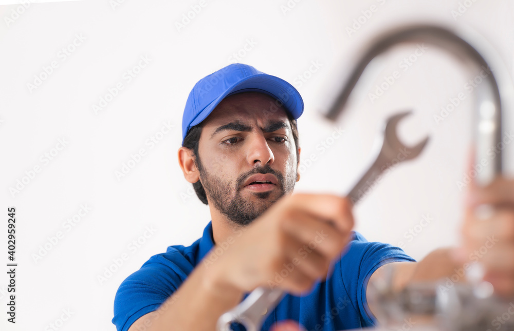 A PLUMBER LOOKING CONFUSED WHILE FIXING A BROKEN TAP	