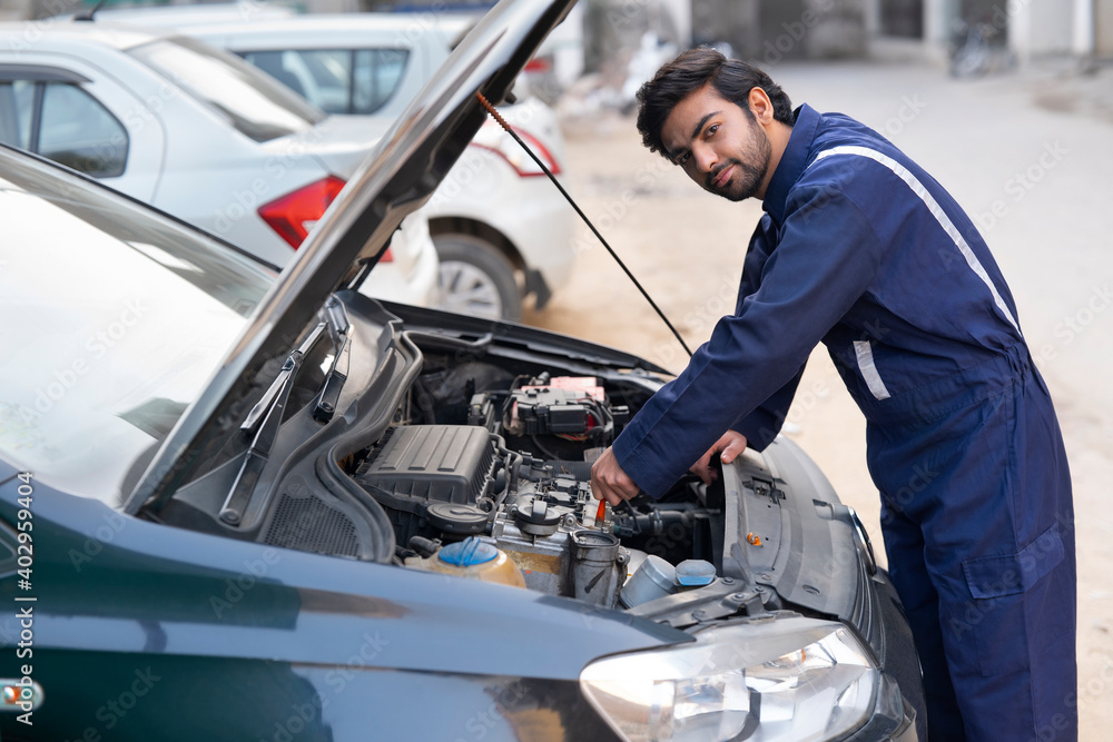 custom made wallpaper toronto digitalA YOUNG MECHANIC LOOKING AT CAMERA WHILE REPAIRING A CAR