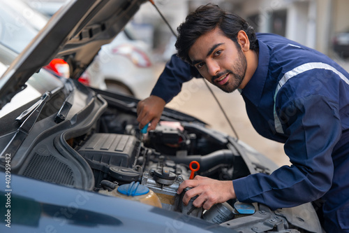 A MECHANIC REPAIRING A CAR AND LOOKING STRAIGHT 