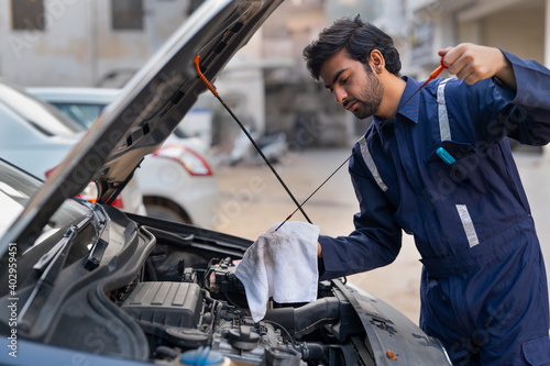 A MECHANIC HOLDING TOOLS TO REPAIR A CAR 