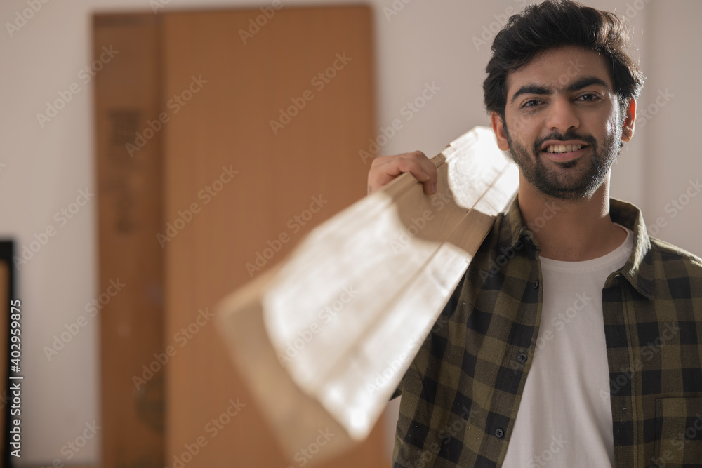 A HAPPY CARPENTER POSING AND LOOKING AT CAMERA HOLDING A STACK OF WOOD A HAPPY CARPENTER POSING AND LOOKING AT CAMERA HOLDING A STACK OF WOOD
