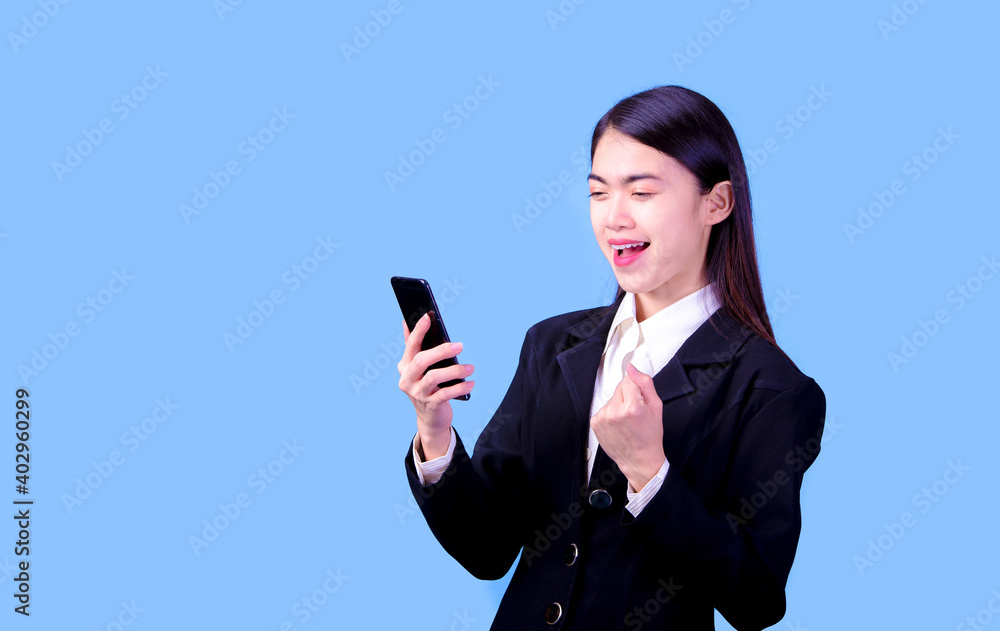 Portrait of Asian woman, happy working day.beautiful modern businesswoman ,holding mobile phon on blue background in the studio Portrait of Asian woman, happy working day.beautiful modern businesswoman ,holding mobile phon on blue background in the studio