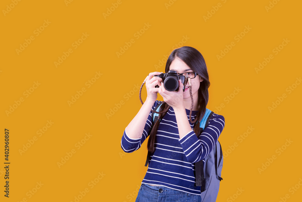 Asian woman tourist was running her to various places.happy excited emotional young woman photographer tourist standing isolated over Orange background Asian woman tourist was running her to various places.happy excited emotional young woman photographer tourist standing isolated over Orange background