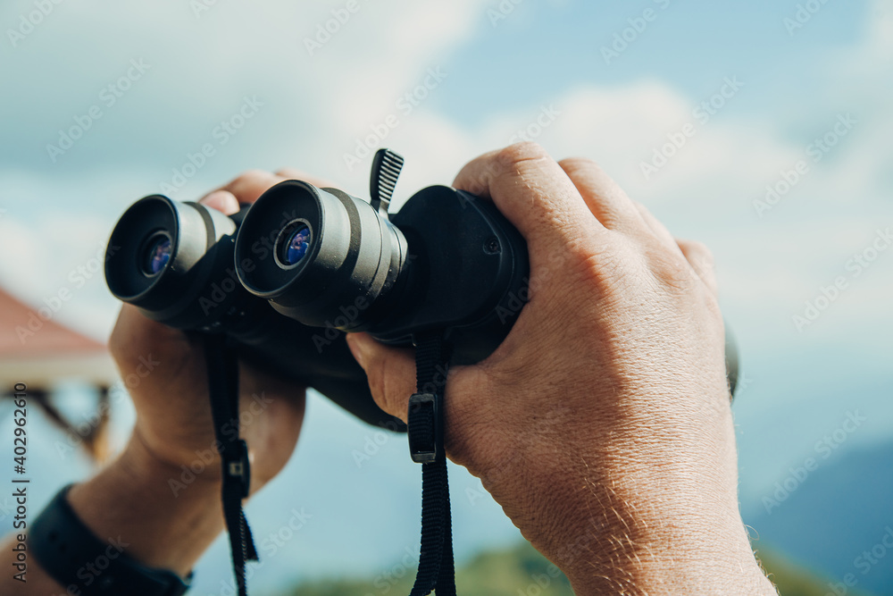 Hands holding binoculars on mountains forest nature background, looking through binoculars, travel, search and search concept. Hands holding binoculars on mountains forest nature background, looking through binoculars, travel, search and search concept.