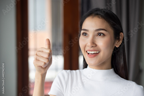 successful girl pointing thumb up, portrait of cheerful smiling woman pointing up approving, yes, ok, good, thumb up gesture by asian Chinese woman young adult model