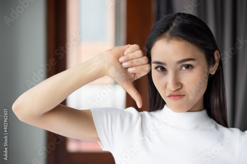 Failed girl pointing thumb down, portrait of unhappy and upset woman pointing rejection thumb down, no, bad, rejecting thumb down gesture by asian Chinese woman young adult model