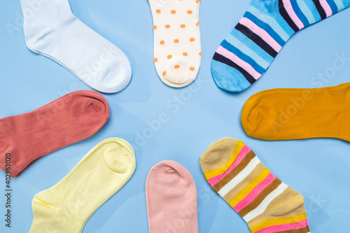 Many socks are piled in a circle in blue background. View from above.