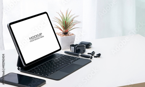 Mockup black screen tablet with magic keyboard, smartwatch and earphone on white top table, copy space. © NAMPIX