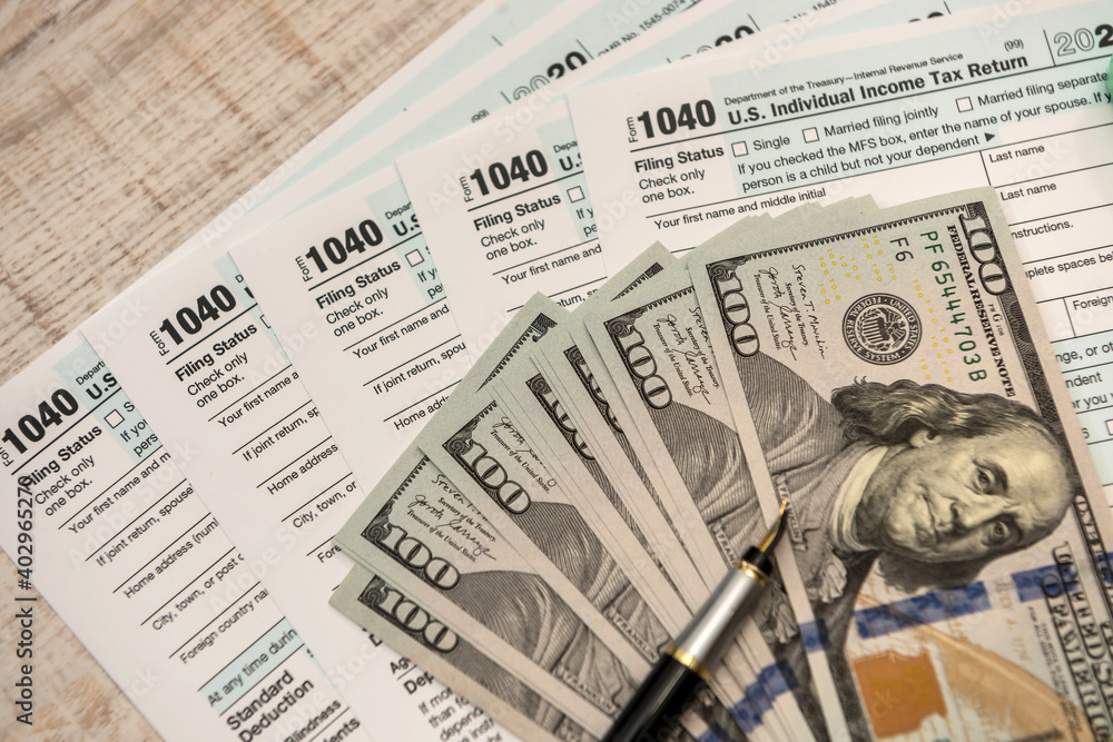 Naklejka premium dollar bills on 1040 tax form. financial concept