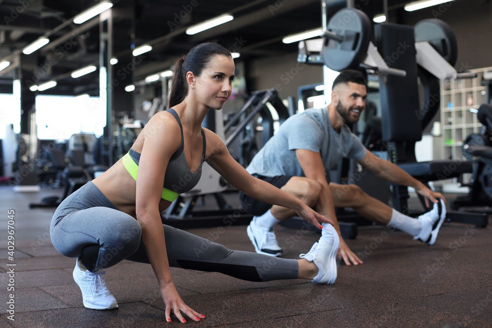 Two fit people doing stretching exersices in crossfit gym. Two fit people doing stretching exersices in crossfit gym.