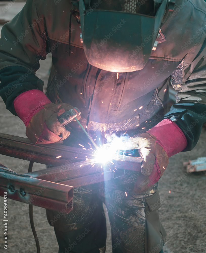 A worker welds metal for a canopy. A worker welds metal for a canopy.