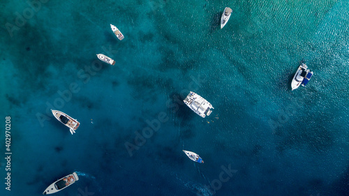 Catamaran sailing in blue, turquoise water in Greece, beautiful catamaran next to the coast during summer holiday, view from drone