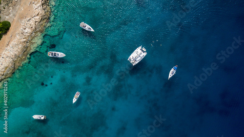 Catamaran sailing in blue, turquoise water in Greece, beautiful catamaran next to the coast during summer holiday, view from drone