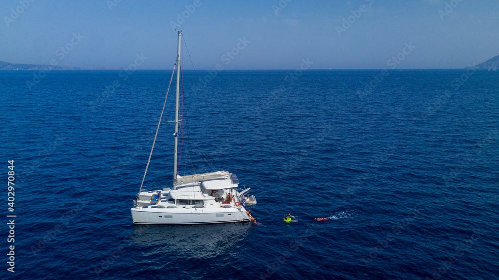 Catamaran sailing in blue, turquoise water in Greece, beautiful catamaran during summer holiday, view from drone Catamaran sailing in blue, turquoise water in Greece, beautiful catamaran during summer holiday, view from drone