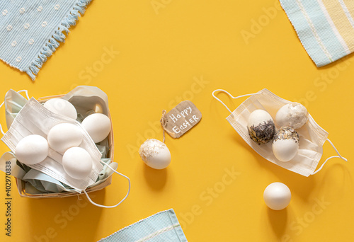 Easter composition with protective masks and scattered Easter eggs top view. photo