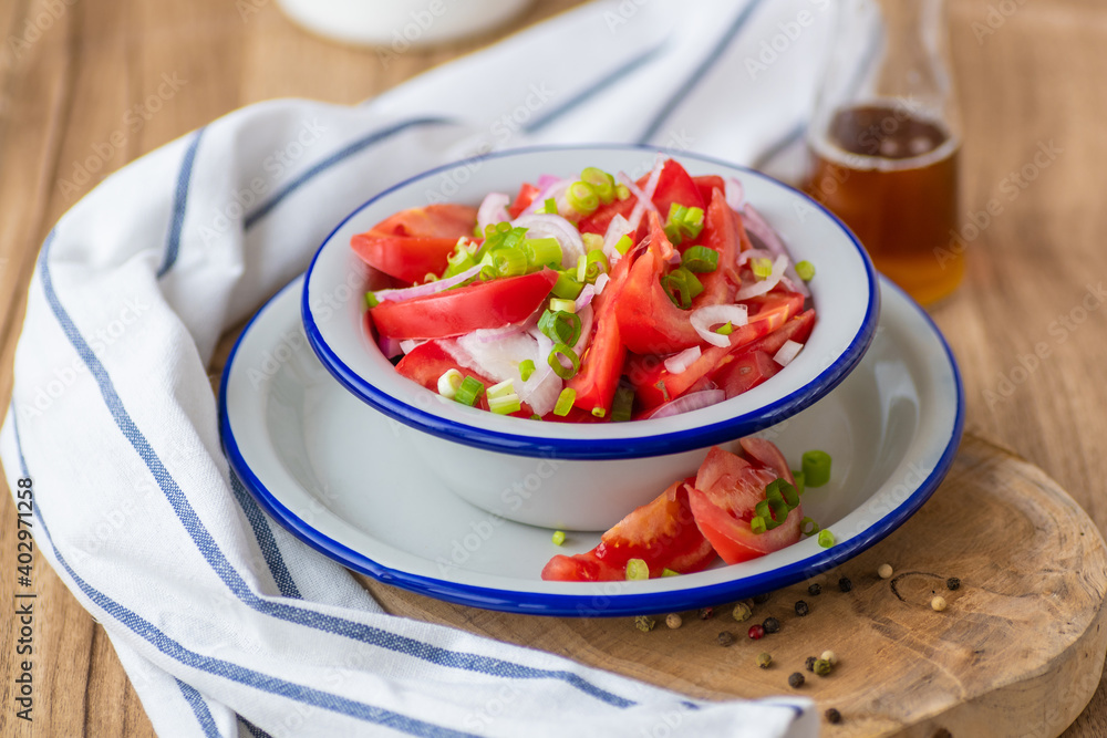 Fresh ripe juicy red tomato salad with green onions and vegetable oil.