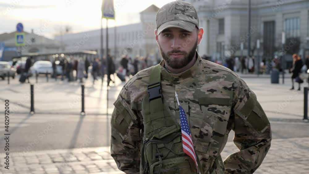 Attractive soldier in uniform and a beard adjusts his cap and looks at the camera at the train station. An American soldier goes to the army. Attractive soldier in uniform and a beard adjusts his cap and looks at the camera at the train station. An American soldier goes to the army.