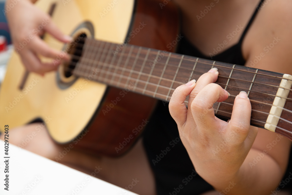 Close up of female hand playing guitar at home Close up of female hand playing guitar at home